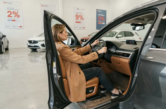 Femme assise dans un SUV neuf lors d'un essai en concession pendant une période de promotions automobiles